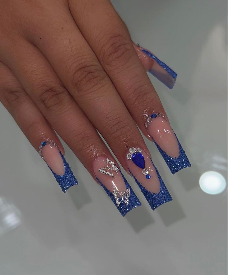 Chic Blue Glitter and Nude Nail Design with Gradient Tips and Gemstone Accents