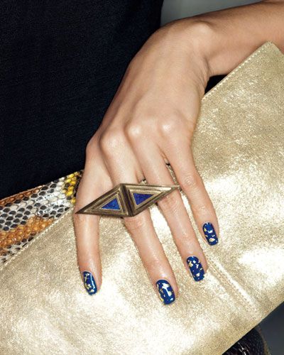 Bold Blue Nail Design with Geometric Accessories Exudes Elegance and Creativity.