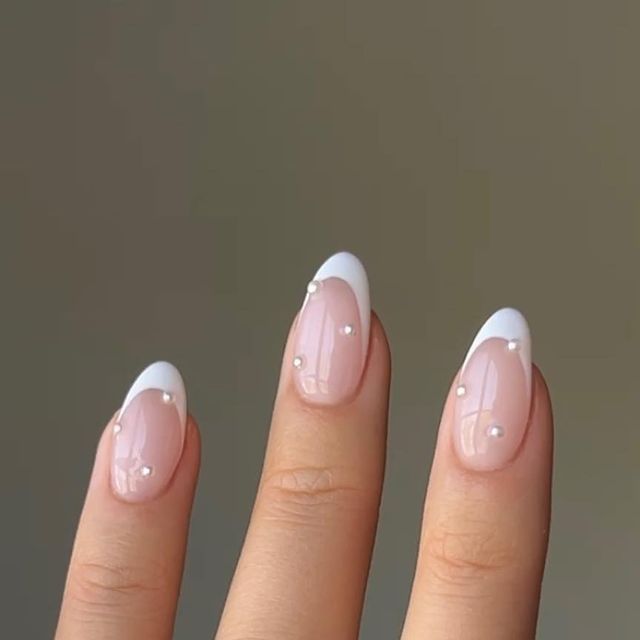 Sophisticated Nude and White Nail Design with Glamorous Embellishments for Any Occasion.