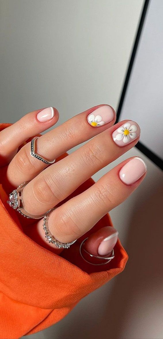 Chic Floral Nail Design: Subtle Nude Base with Delicate Accents and Silver Ring Accents.