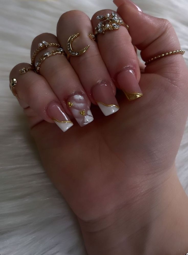 Sophisticated Nail Design with Glossy French Tips and Floral Detail, Accented by Ornate Rings.