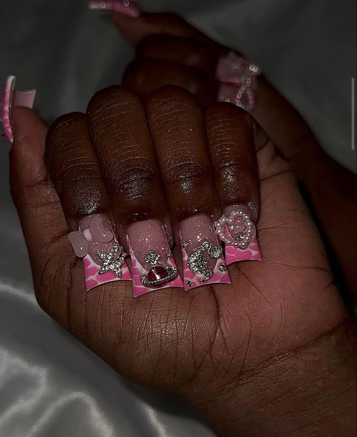 Playful and Vibrant Pink-Tip Nail Design with Unique Charms and Embellishments.