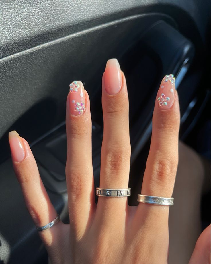 Chic Nude Nail Design with Pastel Floral Accents and Sparkling Rhinestones.