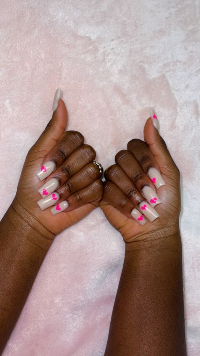 Chic Nude Nails with Playful Pink Heart Accents for a Fun, Sophisticated Look.