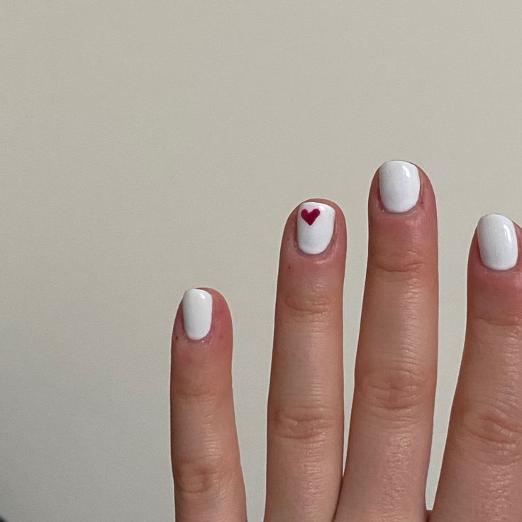 Chic White Nail Design with Whimsical Red Heart Accent