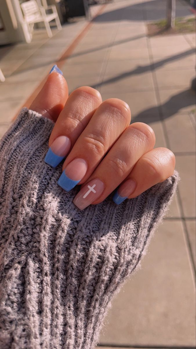 Chic Nude and Pastel Blue Manicure with Elegant Tips and Unique Cross Accent.