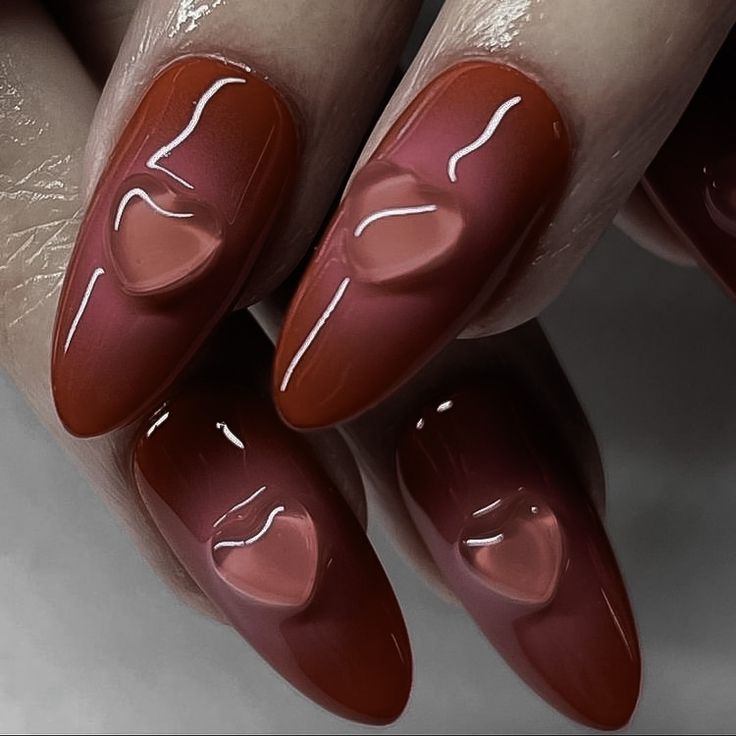 Elegant Almond-Shaped Nails with Glossy Gradient in Warm Red and Intricate Heart Designs.