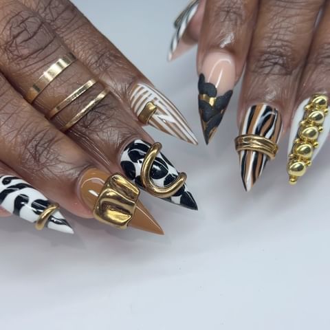 Bold Black and White Stiletto Nail Art with Glamorous Gold Accents.