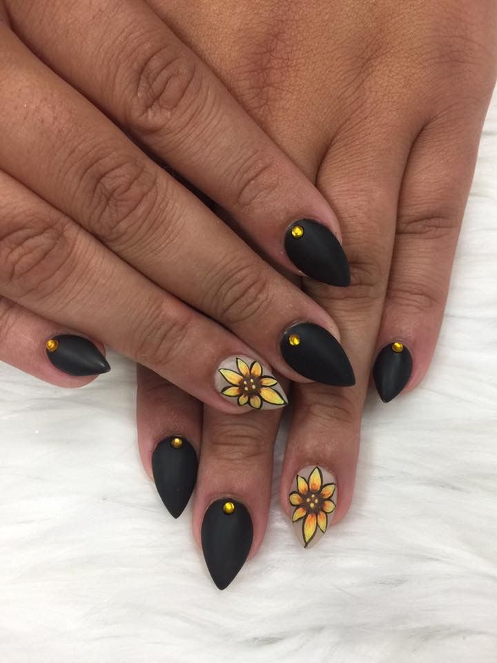 Elegant Matte Black Nails with Vibrant Floral Designs and Chic Gold Studs.