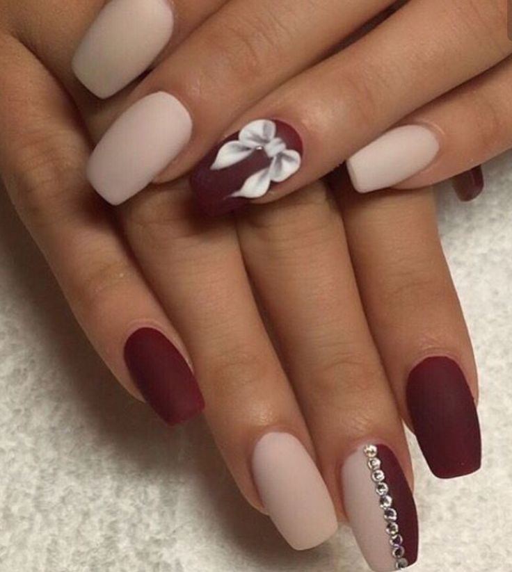 Sophisticated Nail Design: Soft Beige and Rich Burgundy with White Bow and Rhinestone Accents