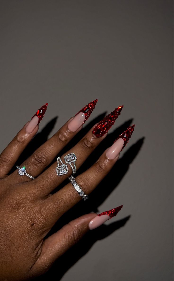 Glamorous Nail Design: Striking Glossy Nude with Bold Glittering Red Accents and Elegant Rings.