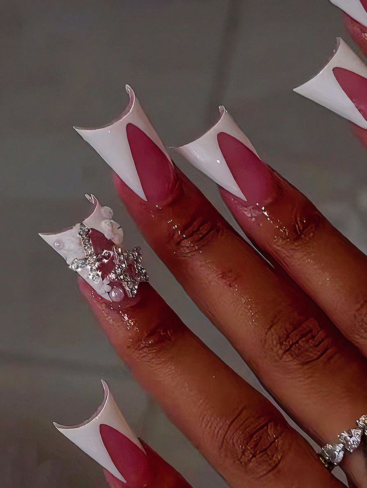 Sophisticated Stiletto Nail Design: Soft Pink and Glossy White with Rhinestones and Pearls.