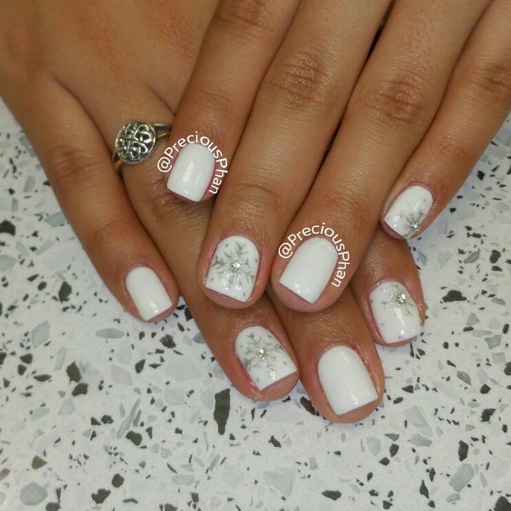 Sophisticated White Nail Design with Subtle Snowflakes and Sparkling Accents for Winter Charm.