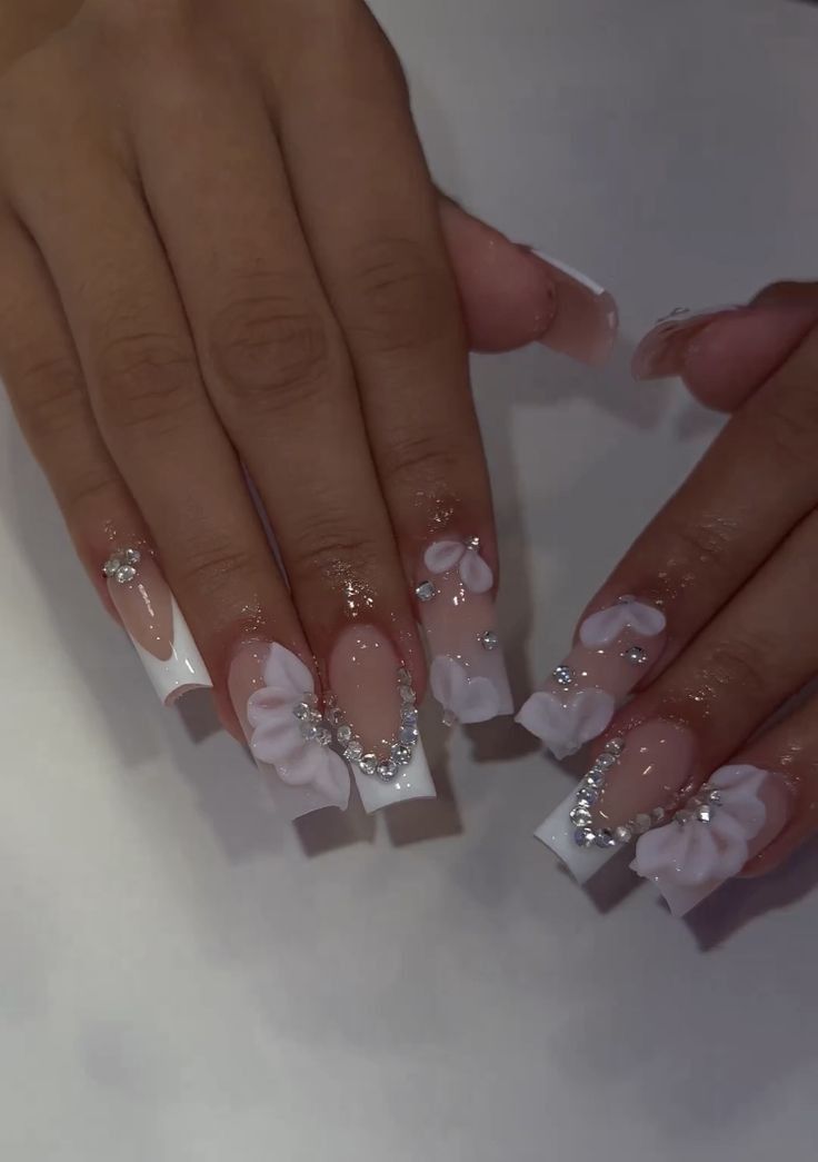 Sophisticated Nude and White Nail Design with Floral Accents and Rhinestones