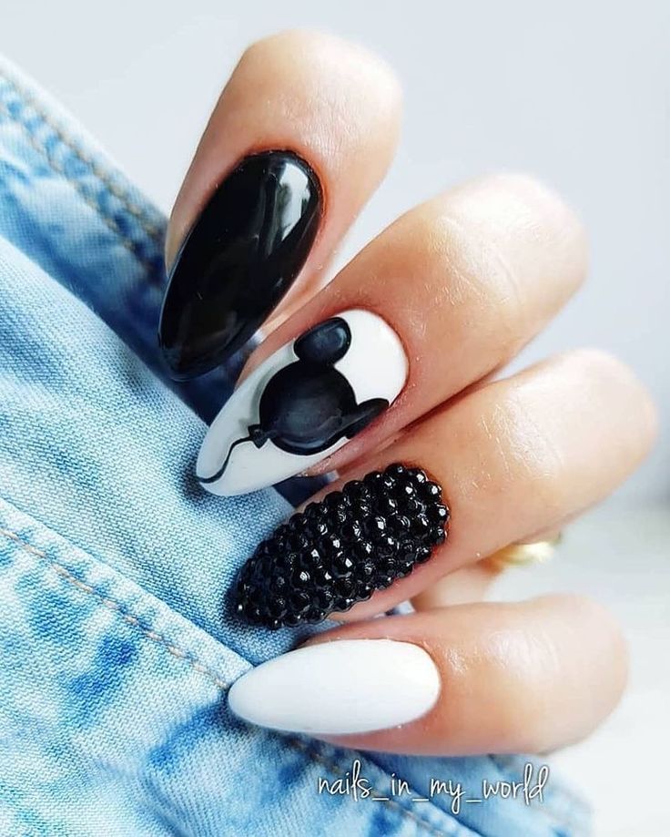 Playful Black and White Nail Design with Whimsical Illustration and Glamorous Rhinestones.