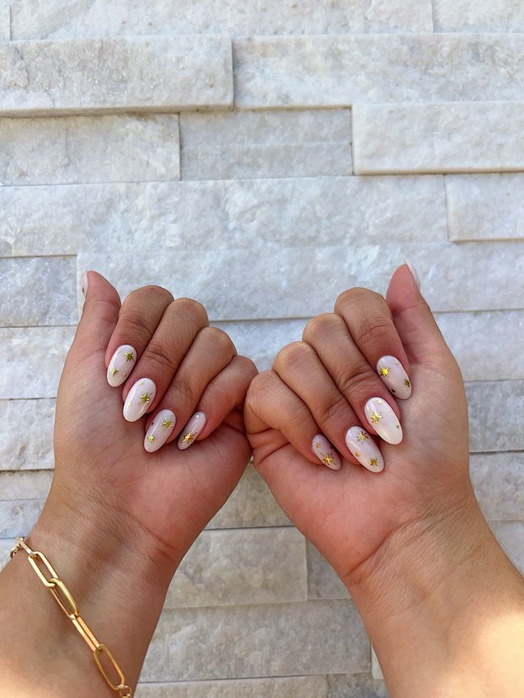 Chic Almond-Shaped Manicure: Soft Nude Base with Floral Accents and Gold Detailing