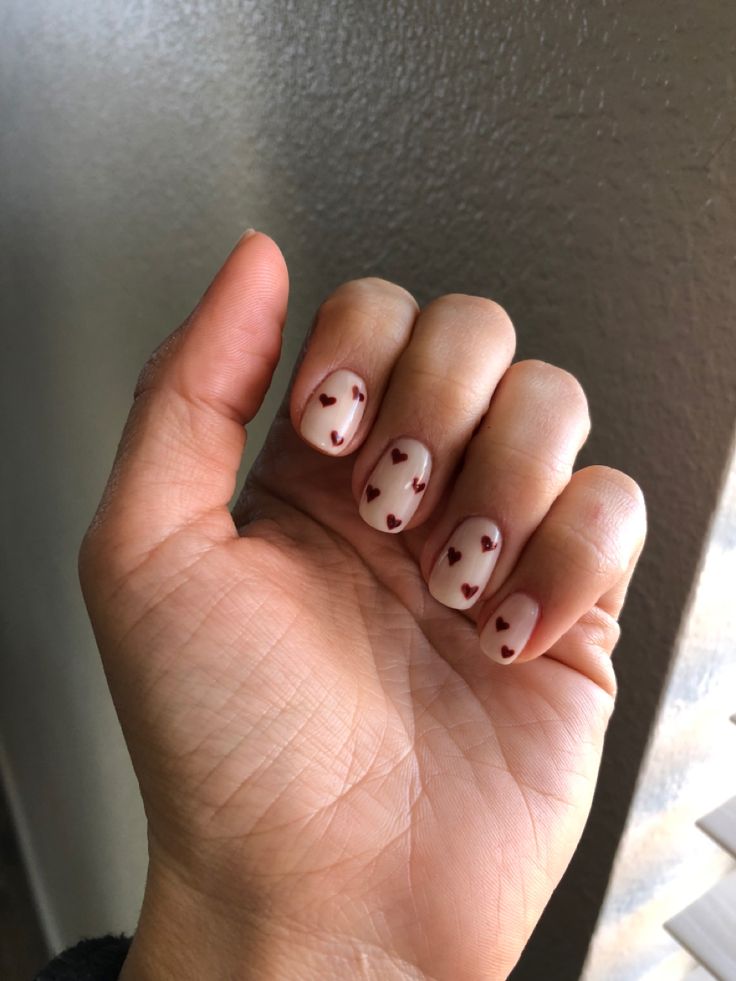 Charming Heart-Themed Nail Design: Soft Nude Base with Adorable Maroon Hearts for Playful Elegance