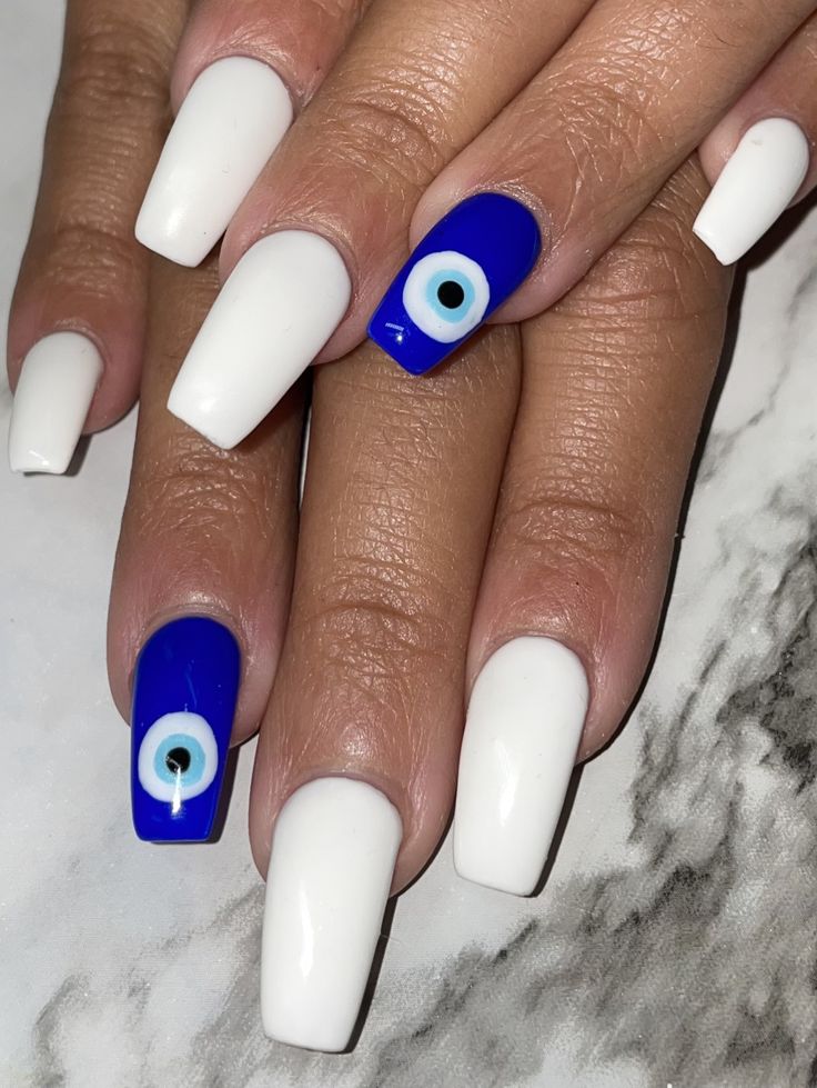 Chic White and Royal Blue Nail Design with Unique Eye Motif Accent.