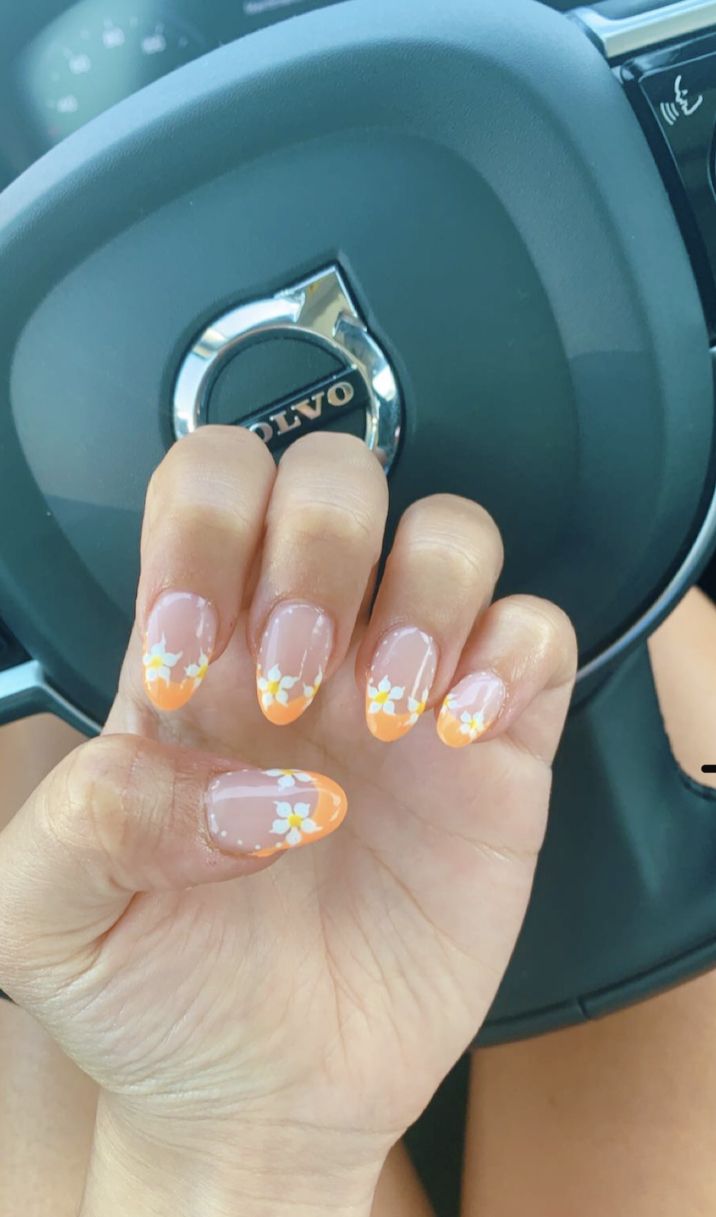 Charming Floral Nail Design: Soft Peachy-Orange Tips with Delicate White Flowers for a Fresh Summer Look.