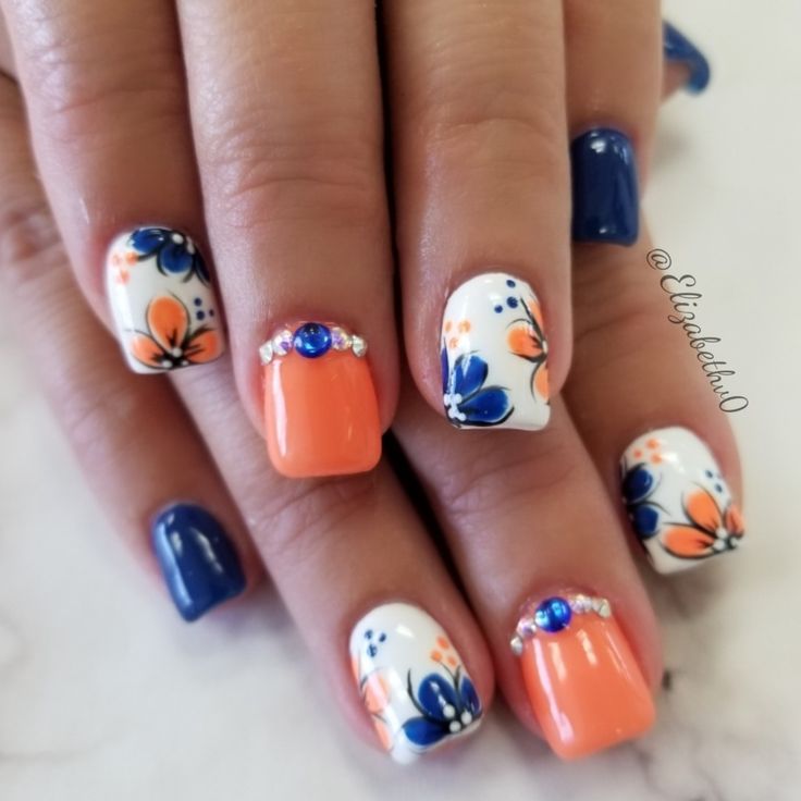 Elegant Vibrant Nail Design with Coral, Navy, White, Floral Patterns, and Rhinestone Accents.