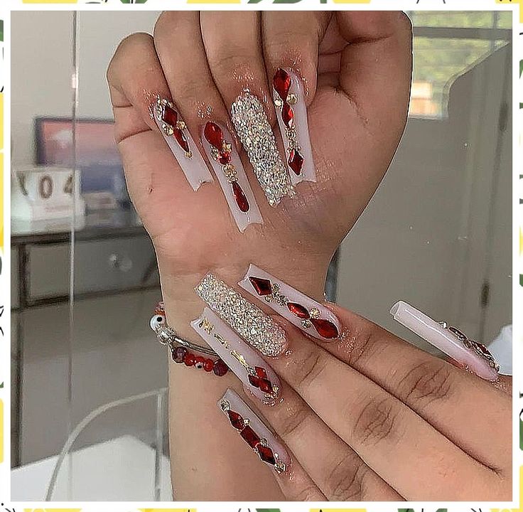 Elegant Elongated Nail Design with Sparkling Rhinestones and Bold Red Gems.