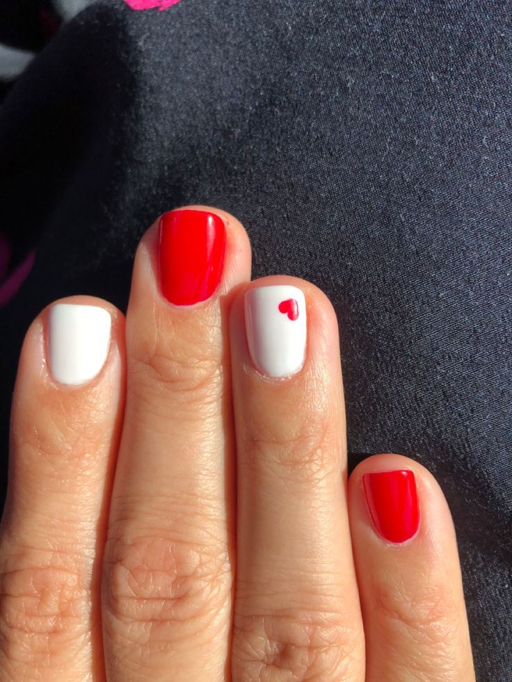 Playful Red and White Nail Design with Charming Heart Accent.