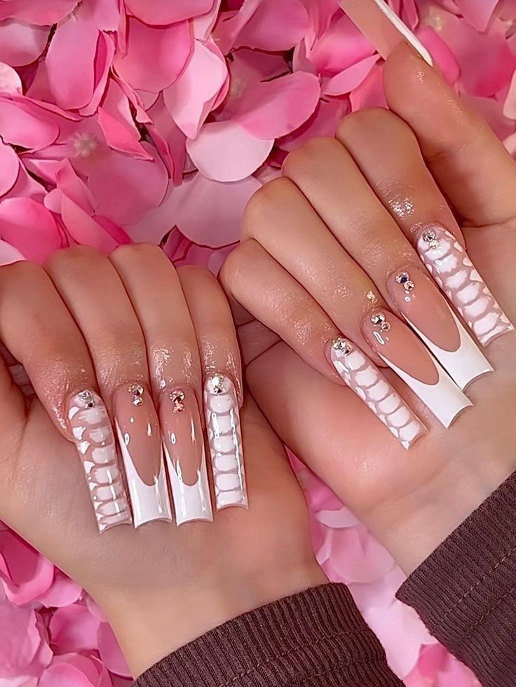 Chic Nail Design with Glossy White and Nude Shades, Intricate Patterns, and Sparkling Rhinestones for a Glamorous Statement.