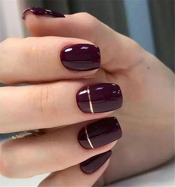 Sophisticated Dark Burgundy Nails with Sleek Gold Accent for Modern Elegance.