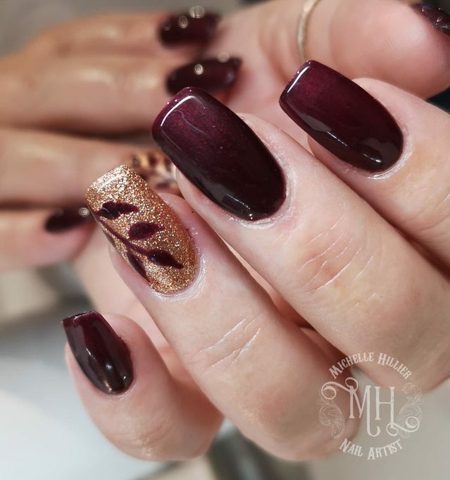 Sophisticated Nail Design: Deep Burgundy with Glittery Gold Accent and Intricate Leaf Patterns