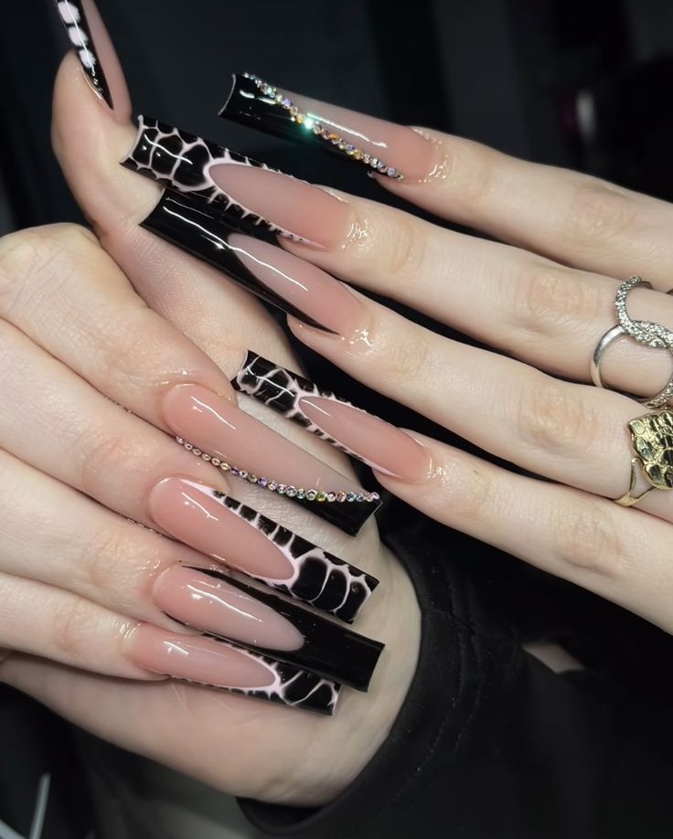 Chic Elegance: Glossy Nude and Black Nail Design with Intricate Patterns and Rhinestones.