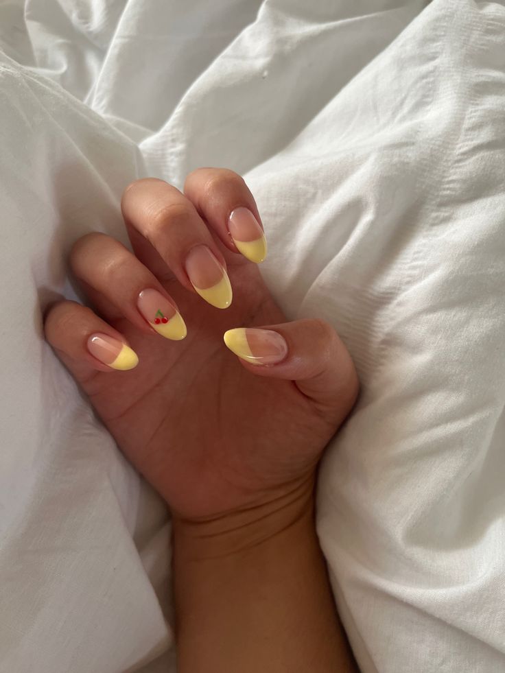 Playful Sunny Yellow French Tip Nail Design with Unique Fruit Motif for a Fresh and Cheerful Aesthetic.