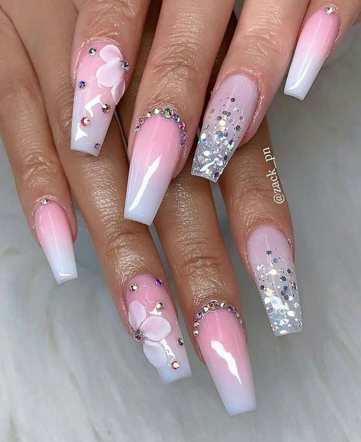 Elegant Pink and White Ombre Nail Design with Floral Accents and Glitter Highlights.