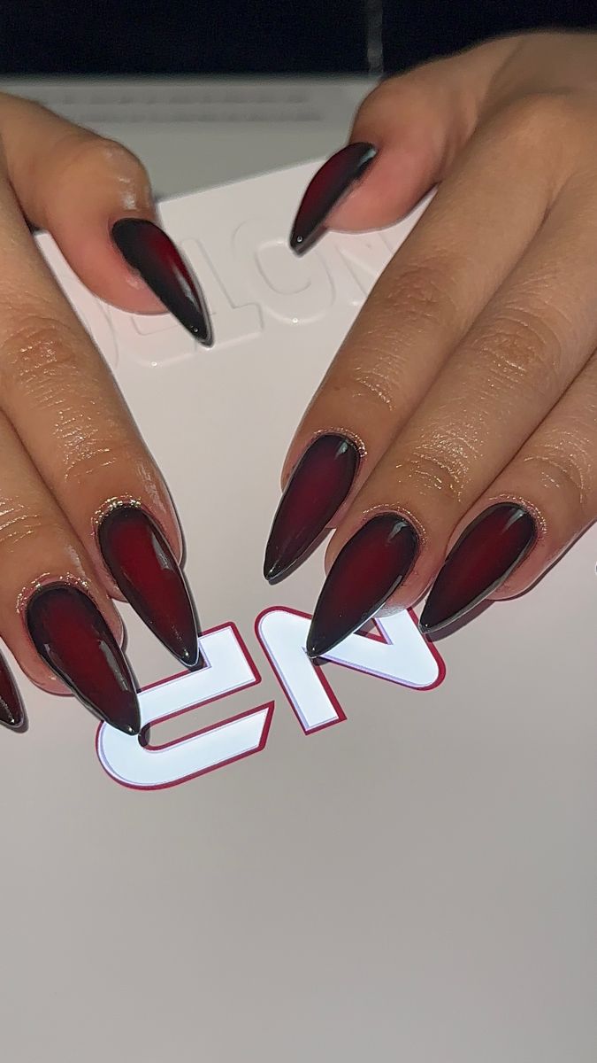 Elegant Almond-Shaped Nails: Deep Burgundy to Glossy Black with Glamorous Gold Accents.