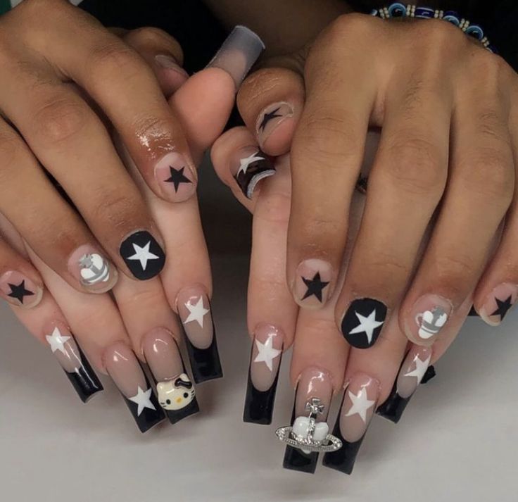 Celestial-Inspired Nail Art: Bold Black and Nude Design with Star and Planet Motifs.