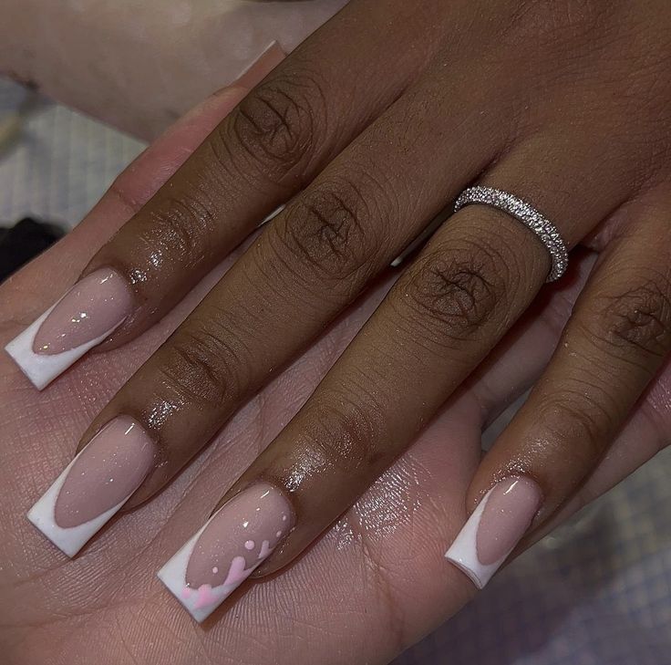 Chic Nude and French Tip Nail Design with Delicate Pink Accents and Sparkling Ring.