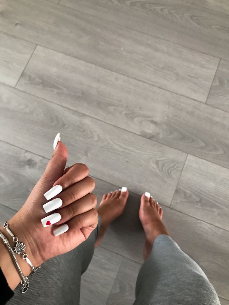 Chic Minimalist White Nail Design with Playful Red Heart Accent.