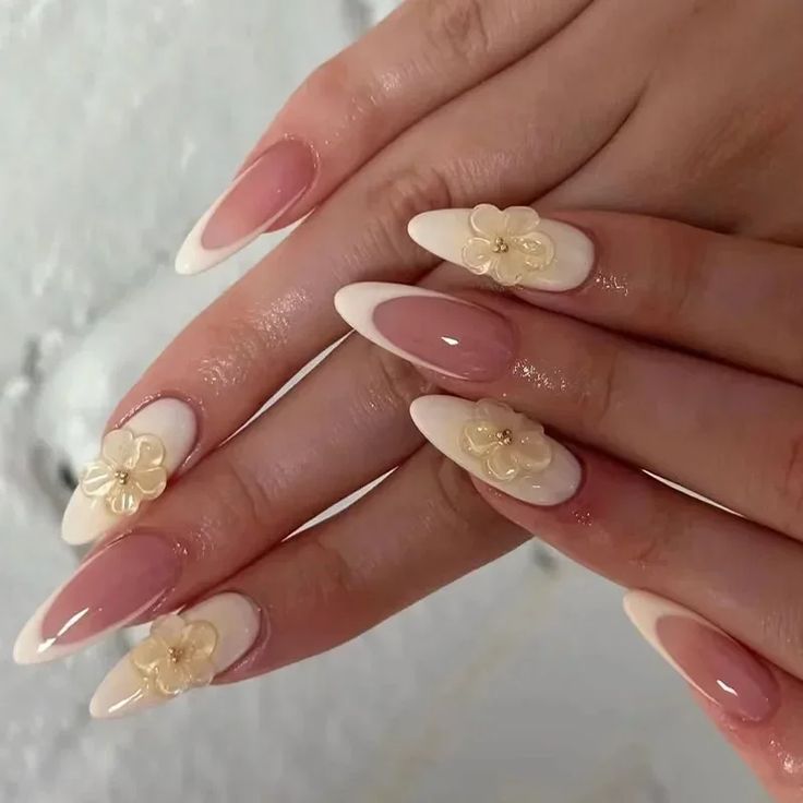 Chic Almond-Shaped Nails: Soft Nude and Creamy White with Floral Embellishments.