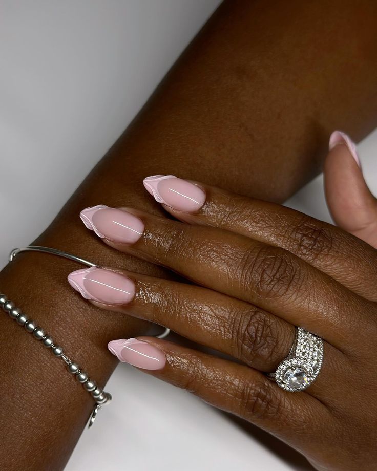 Sophisticated Soft Pink Almond Nail Design with Elegant White Tips and Subtle Jewelry.