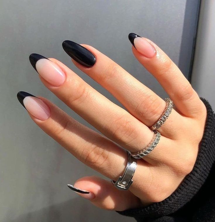 Chic Almond-Shaped Nail Design: Elegant Contrast of Glossy Black Tips and Nude Base with Artistic Flair.