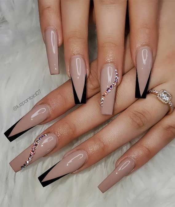 Chic Almond-Shaped Manicure: Nude and Black Polished Nails with Rhinestone Accents.