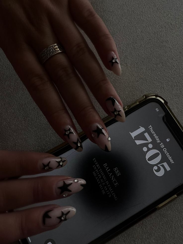 Chic Nude and Black Star Nail Design with Glamorous Embellishments.