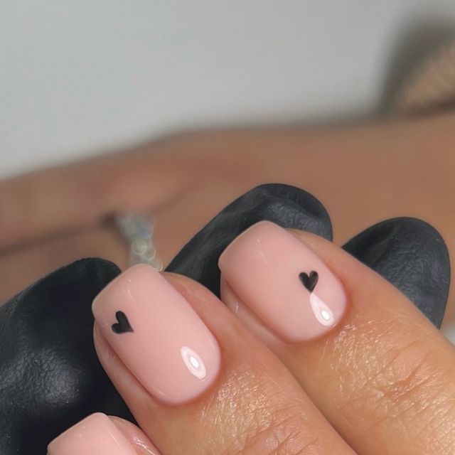 Chic Pink Nail Design with Minimalist Black Heart Accents for a Stylish Look.