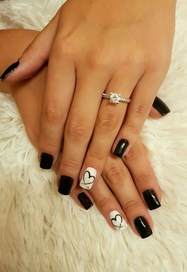 Elegant Black and White Nail Design with Heart and Cross Accent.