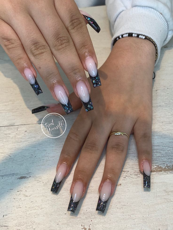 Chic Ombre Nails: Soft Nude Base with Black French Tips and Sparkling Embellishments.