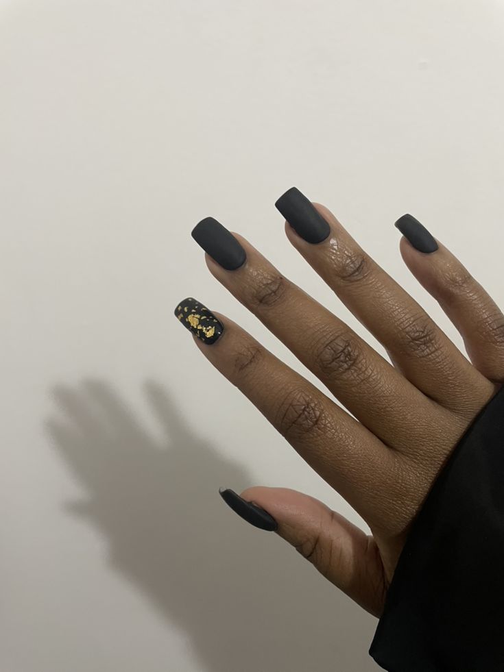 Sleek Matte Black Nails Enhanced by Glamorous Gold Accent for a Chic Look.