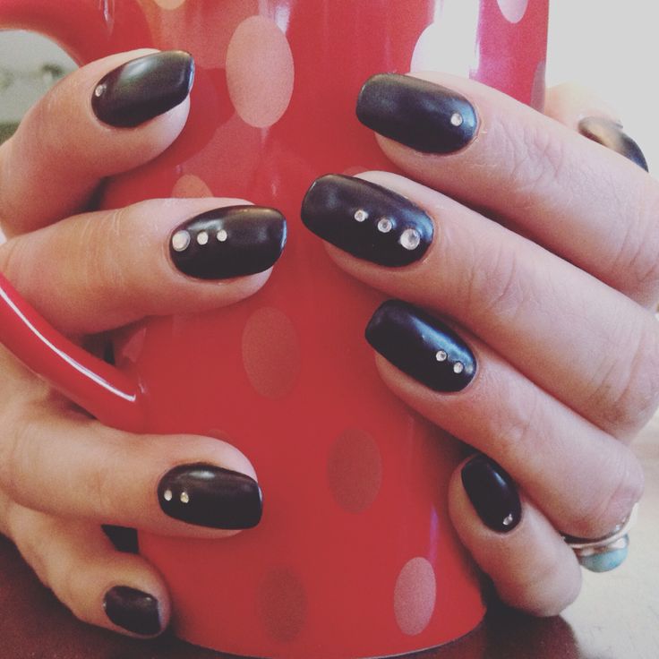 Chic Black Nail Design with Glossy Finish and Silver Stud Accents, Enhanced by a Vibrant Dotted Cup.