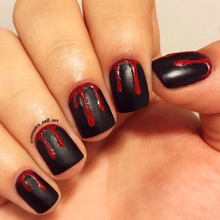 Bold Matte Black Nail Design with Glossy Red Drip Accents for a Unique Statement.