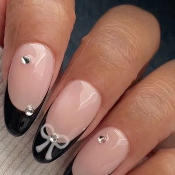 Chic Nude and Black Nail Design with White Bow and Rhinestones for a Glamorous Look