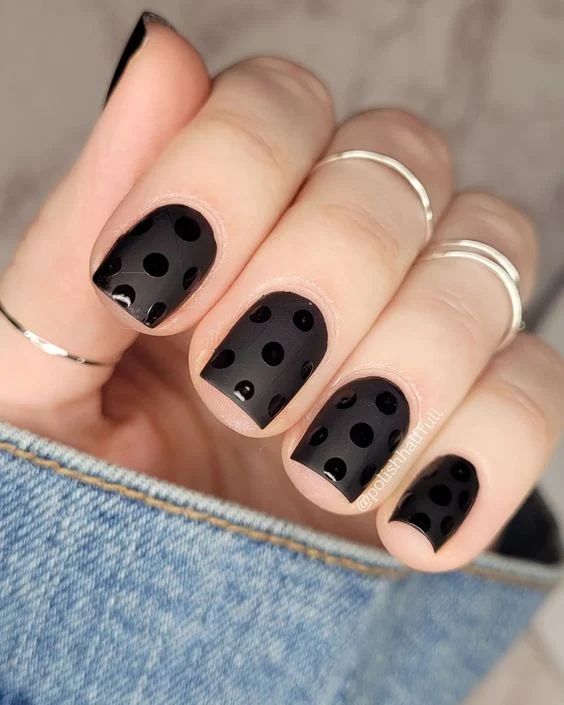 Chic Black Nail Design with Glossy Polka Dots and Elegant Ring Accents.