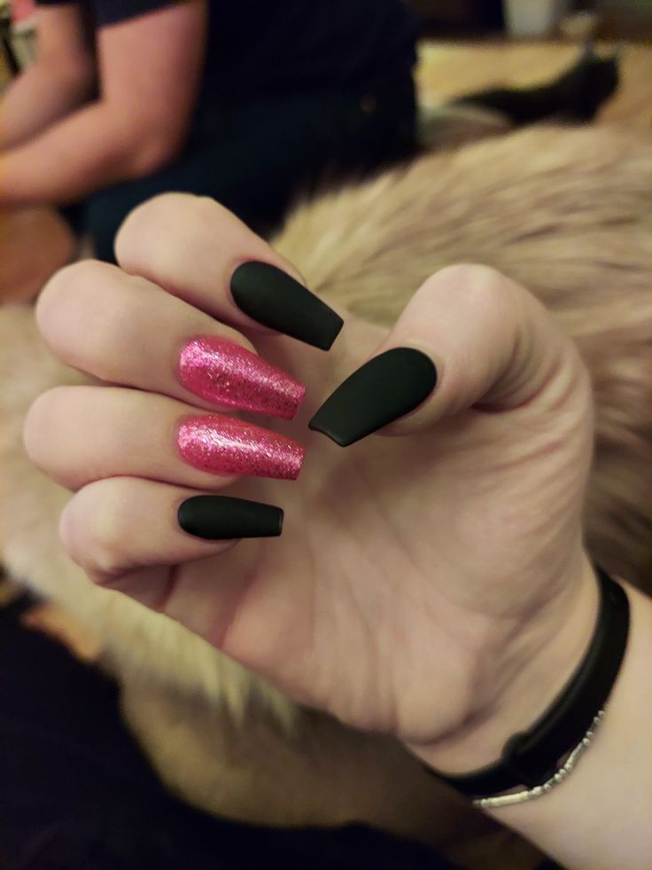 Bold Matte Black and Bright Pink Glitter Almond Nail Design.